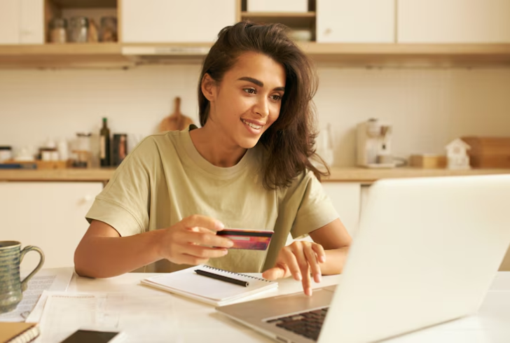 Woman holds bank card at laptop